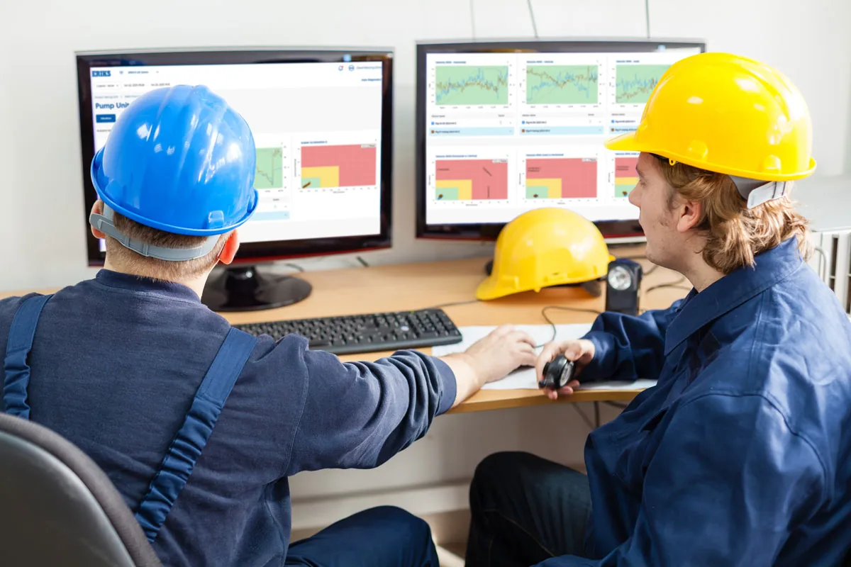 Two workers sitting in front of a computer assessing data on the screen